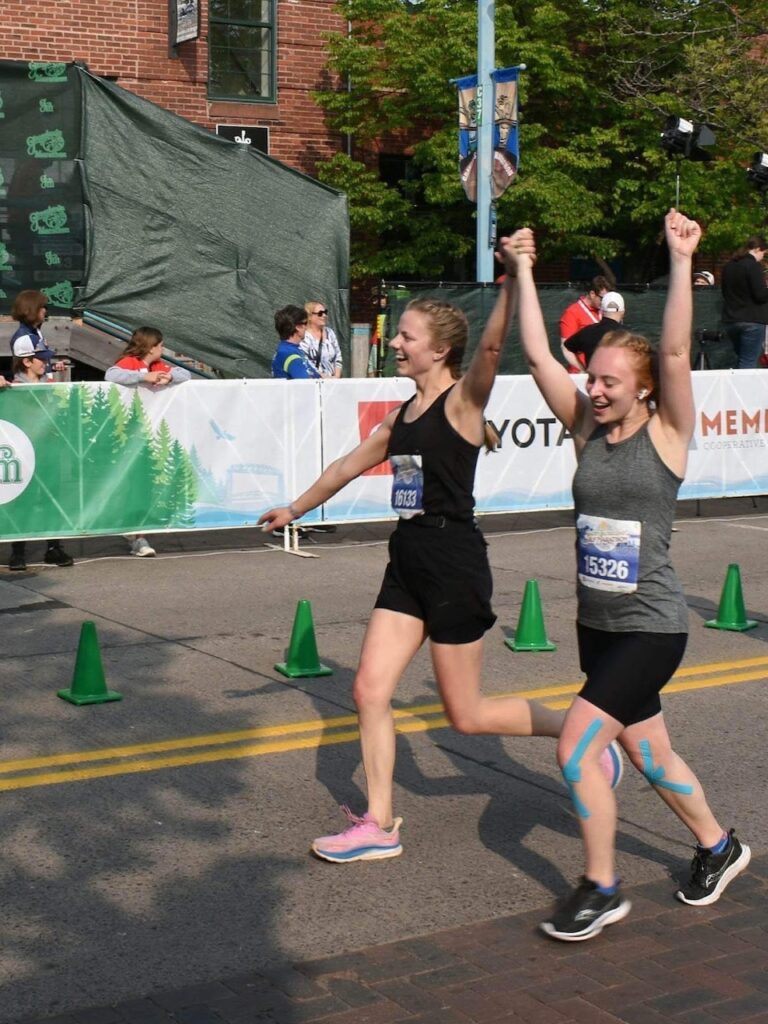 Jill and Kelley cheering after completing an exciting run together. They are raising their hands excitedly in the air.