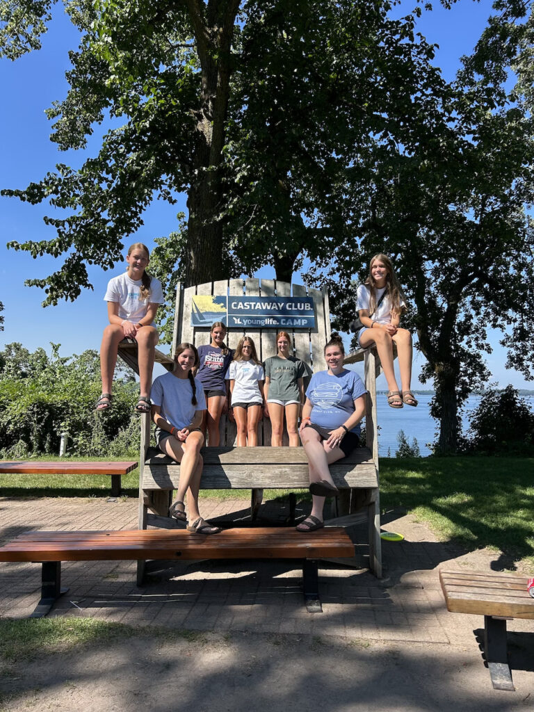 A group of girls with Young Life are sitting on a giant chair